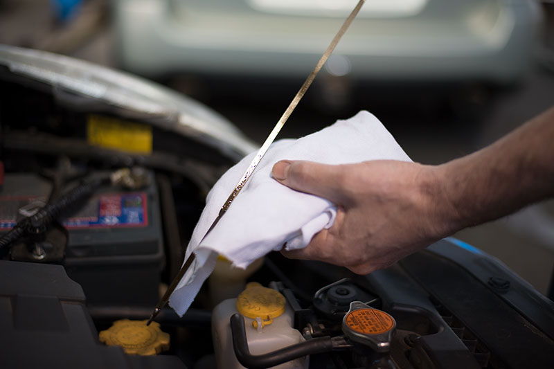 Mechanic cleaning dipstick after checking oil